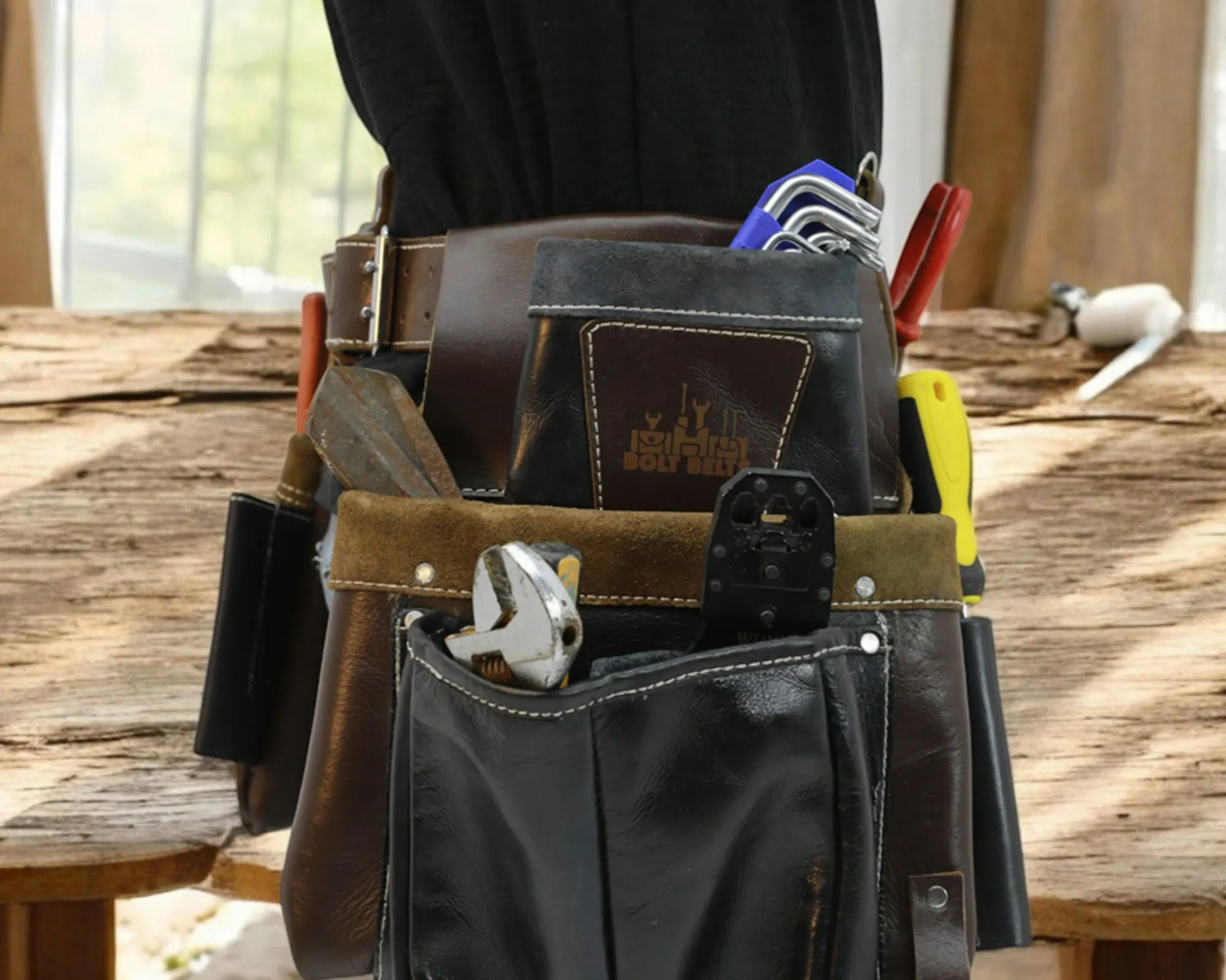 Electrician tool belt hung on a workbench in a garage