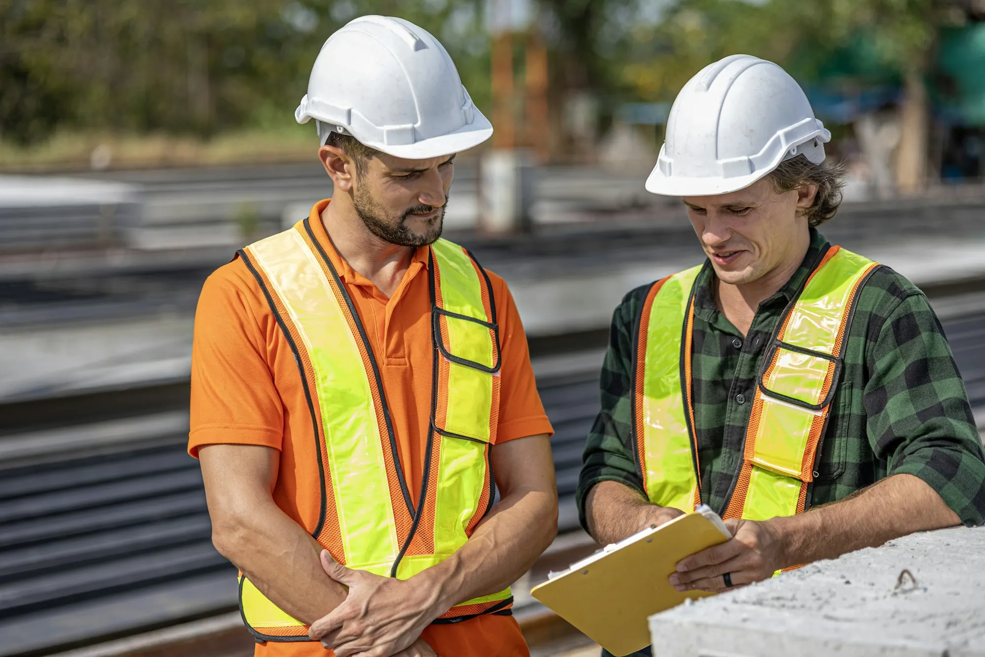 Two electricians in high-visibility vests discussing a job outdoors