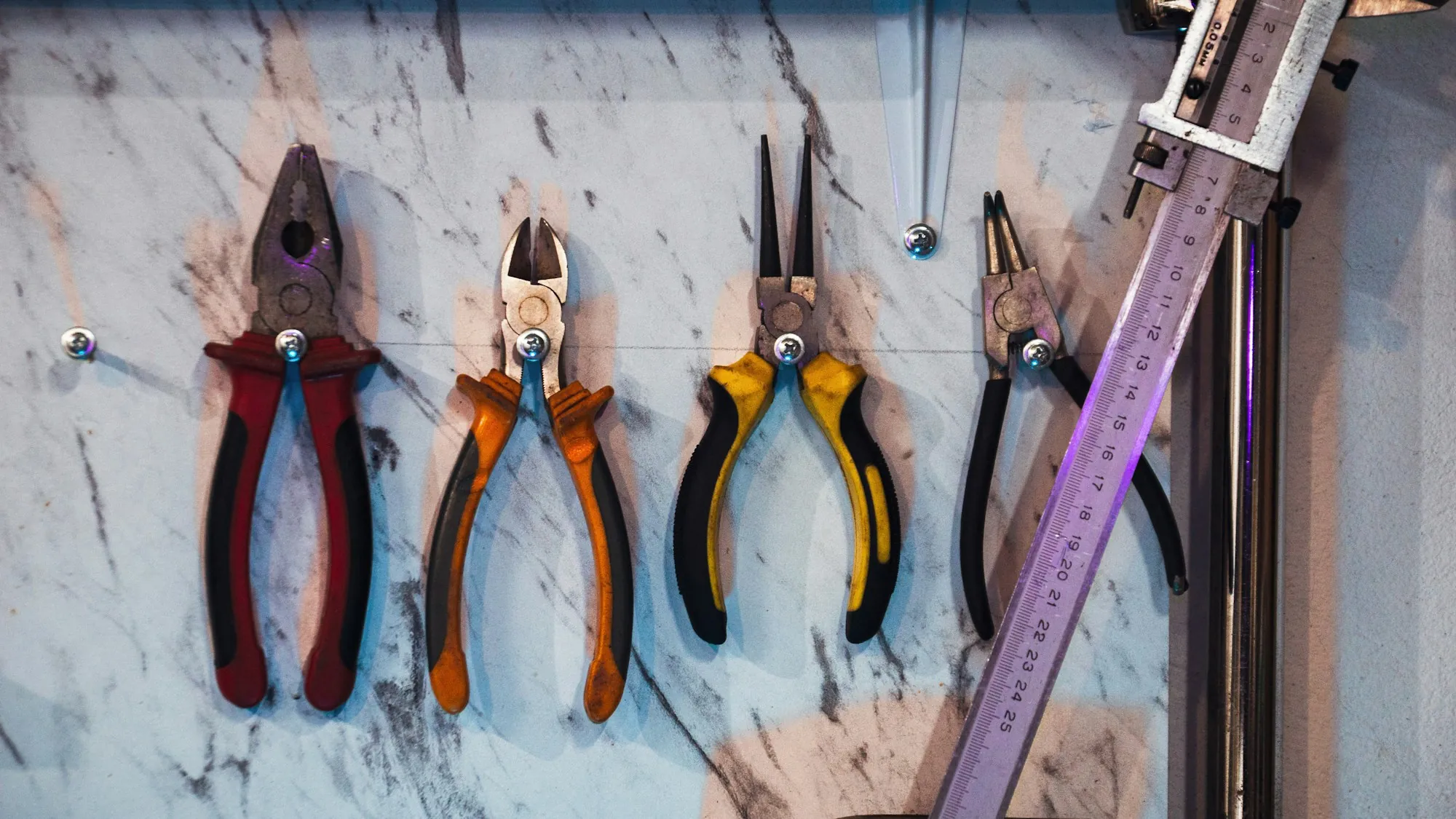 Rows of electrician pliers hanging on a workshop wall