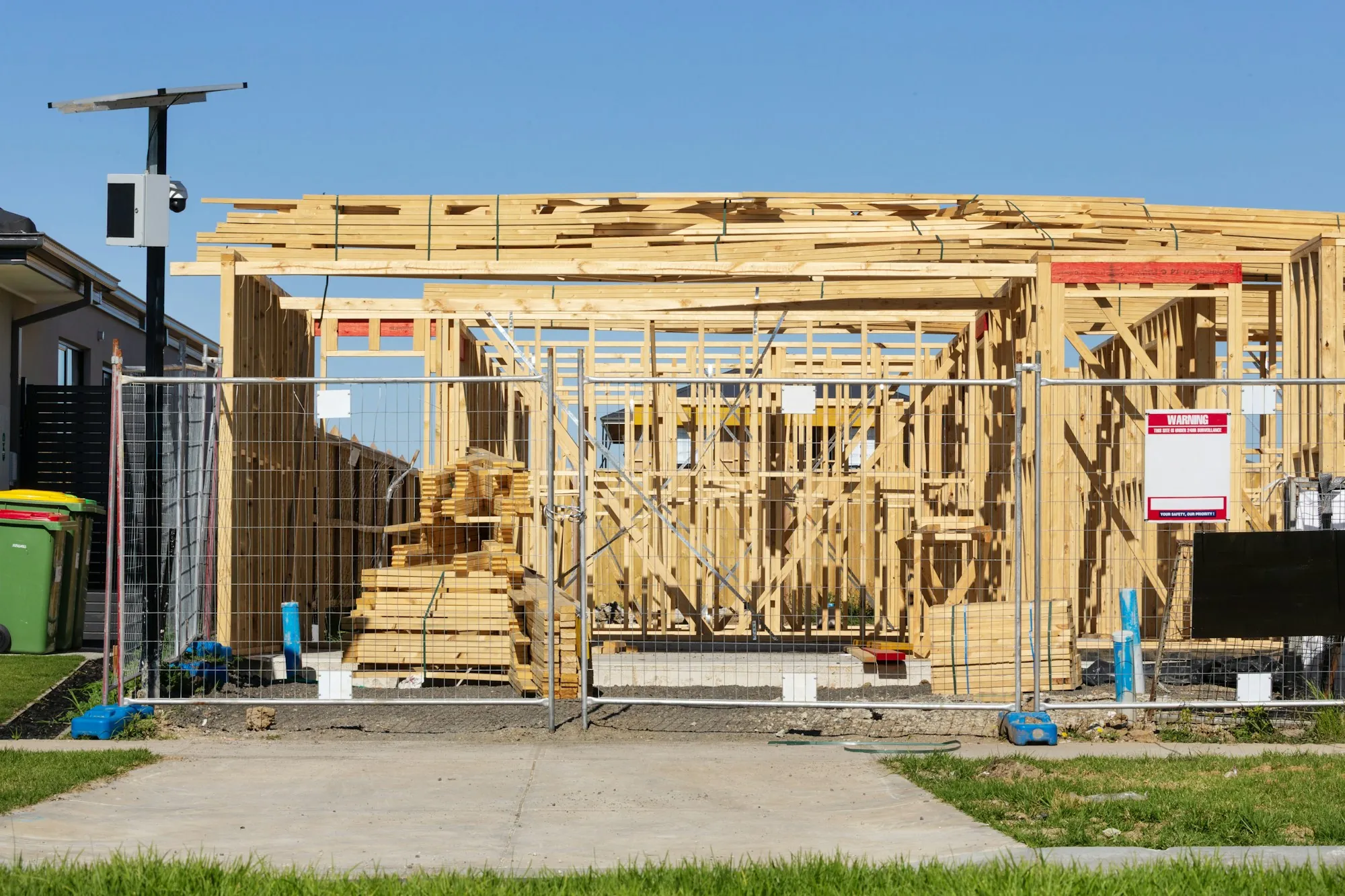 Timber frame of a new house going up behind a construction fence
